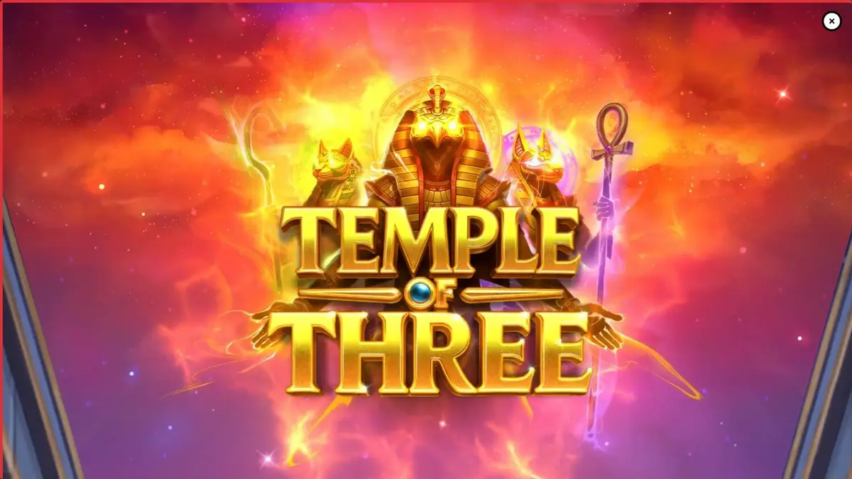 Tampilan layar permainan slot Temple of Three dengan latar belakang makam Mesir kuno yang diterangi obor dan tiga dewa Mesir.